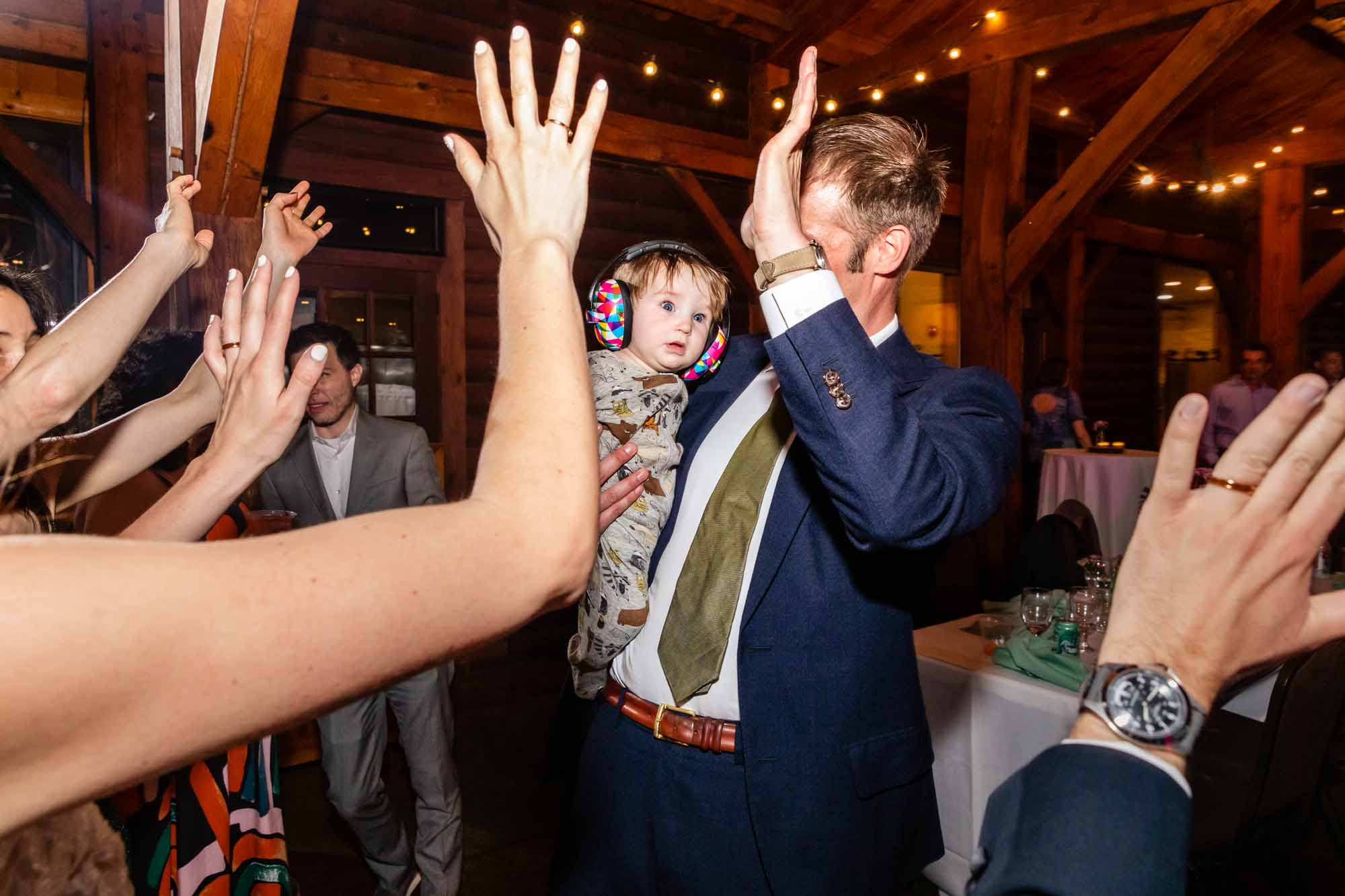baby on a dance floor surrounded by hands and limbs, with a disgusted look on her face. creative image found by a photojournalist wedding photographer!